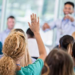 Person holder opp handen i forelesning